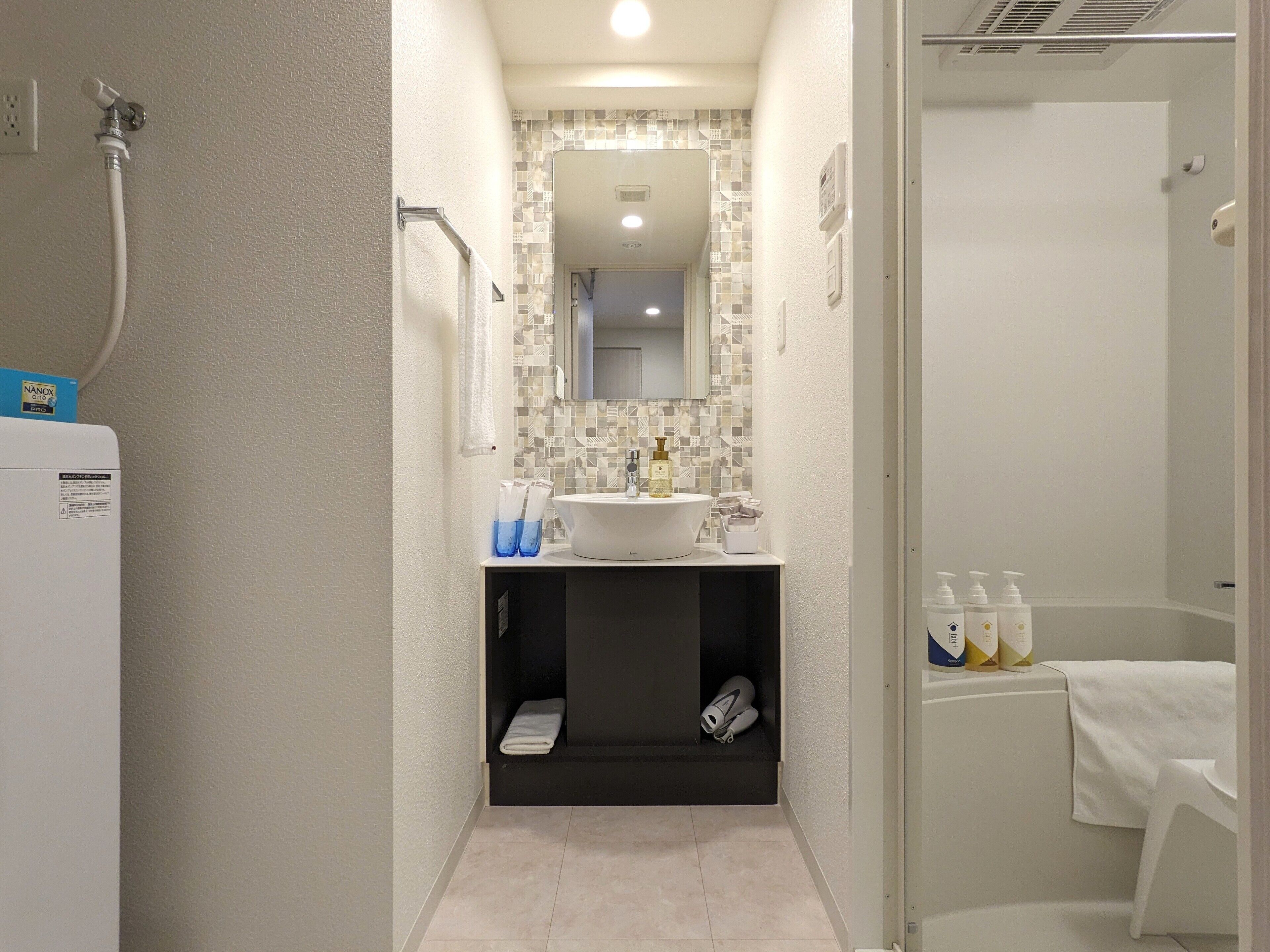 A modern bathroom with a white sink, a mirror, and a shower area.