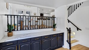 A modern kitchen with dark cabinetry, white countertops, and a black railing. - NEW! Luxe Vacation Getaway - heated pool and putting green (Peoria)