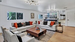 A spacious living room with a large window, a fireplace, and a staircase leading to an upper level. - NEW! Luxe Vacation Getaway - heated pool and putting green (Peoria)
