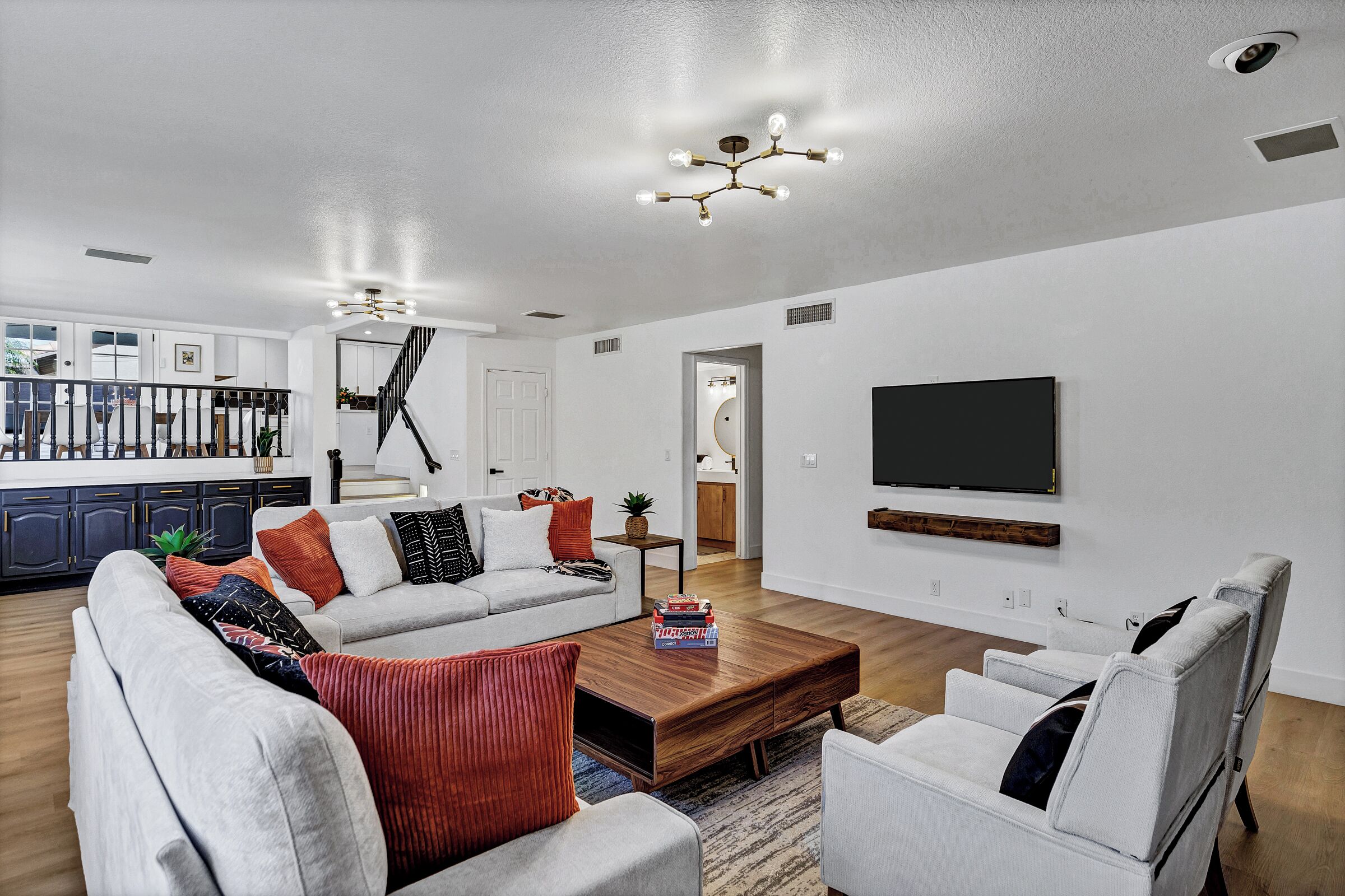 Una sala de estar moderna con un sofá gris, una mesa de centro y un televisor montado en la pared.