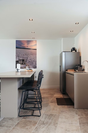 A modern kitchen with a bar area, a refrigerator, and a large window with a view.