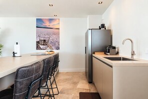 A modern kitchen with a bar area, a refrigerator, and a sink.