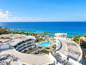 A resort with a central pool, multiple balconies, and a view of the ocean.