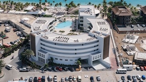 Un hôtel moderne doté d’une piscine circulaire, offrant une vue sur la plage et disposant d’un parking.