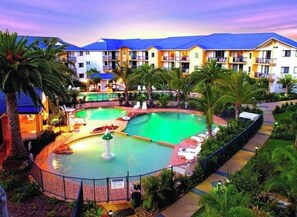A hotel with a swimming pool, palm trees, and a blue-roofed building. - The ultimate Family holiday at Turtle Beach Resort- Mermaid beach (Mermaid Beach)
