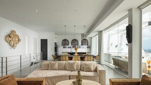 A modern living room with a large beige sectional sofa, a round coffee table, and a dining area with a dark wooden table and wicker chairs. - The Blossom Villa by Elite Havens (Koh Samui)