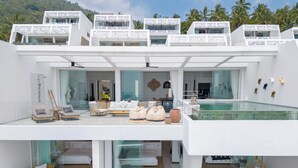 A modern, multi-level residential building with a pool, outdoor seating, and a view of palm trees. - The Blossom Villa by Elite Havens (Koh Samui)