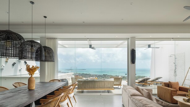 A modern living room with a dining area, large windows, and a view of the ocean. - The Blossom Villa by Elite Havens (Koh Samui)