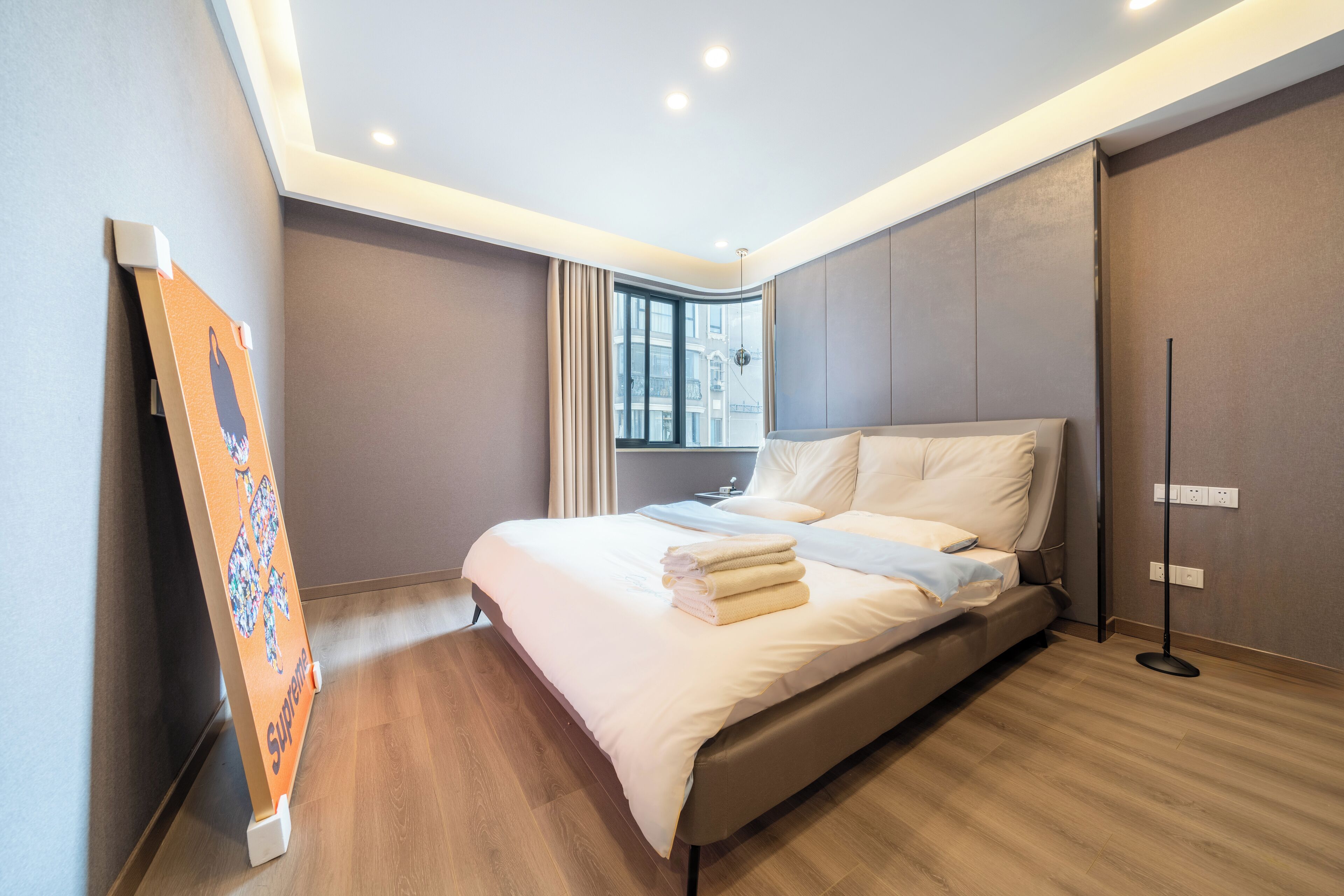 A modern hotel room with a large bed, a standing lamp, and a window with curtains.