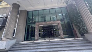 A building entrance with large glass doors, a marble frame, and steps leading up to it.