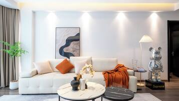 A modern living room with a white sofa, two round coffee tables, a floor lamp, and a decorative sculpture.