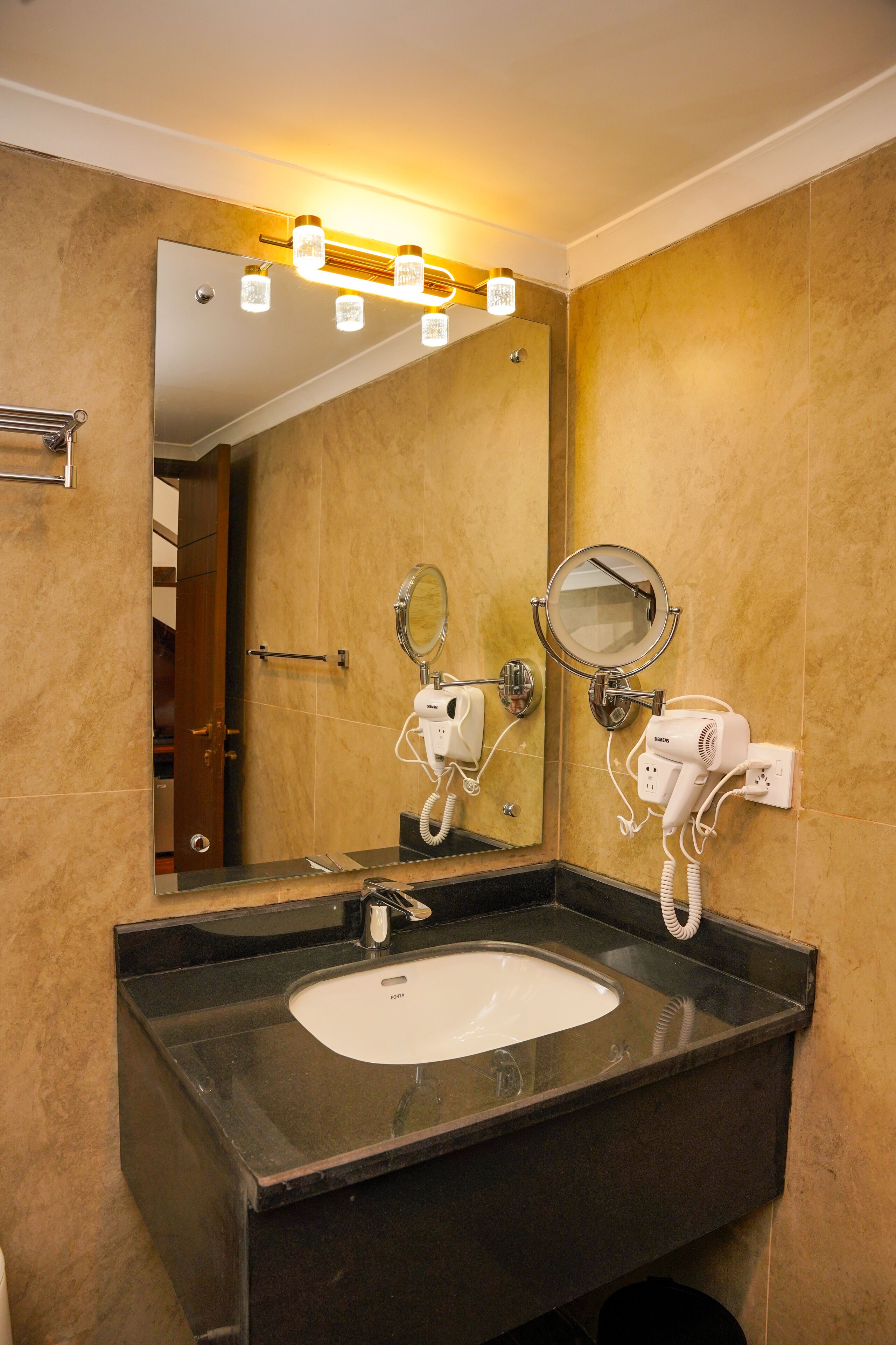 Un baño con un espejo grande, dos secadores de pelo y un lavamanos.