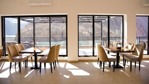 A spacious room with large windows, a dining table, and chairs. - Lodges By Baron Hunza Attabad Lake (Aina Abad)