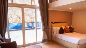 A hotel room with a bed, a small round table, and a view of a blue staircase outside. - Lodges By Baron Hunza Attabad Lake (Aina Abad)