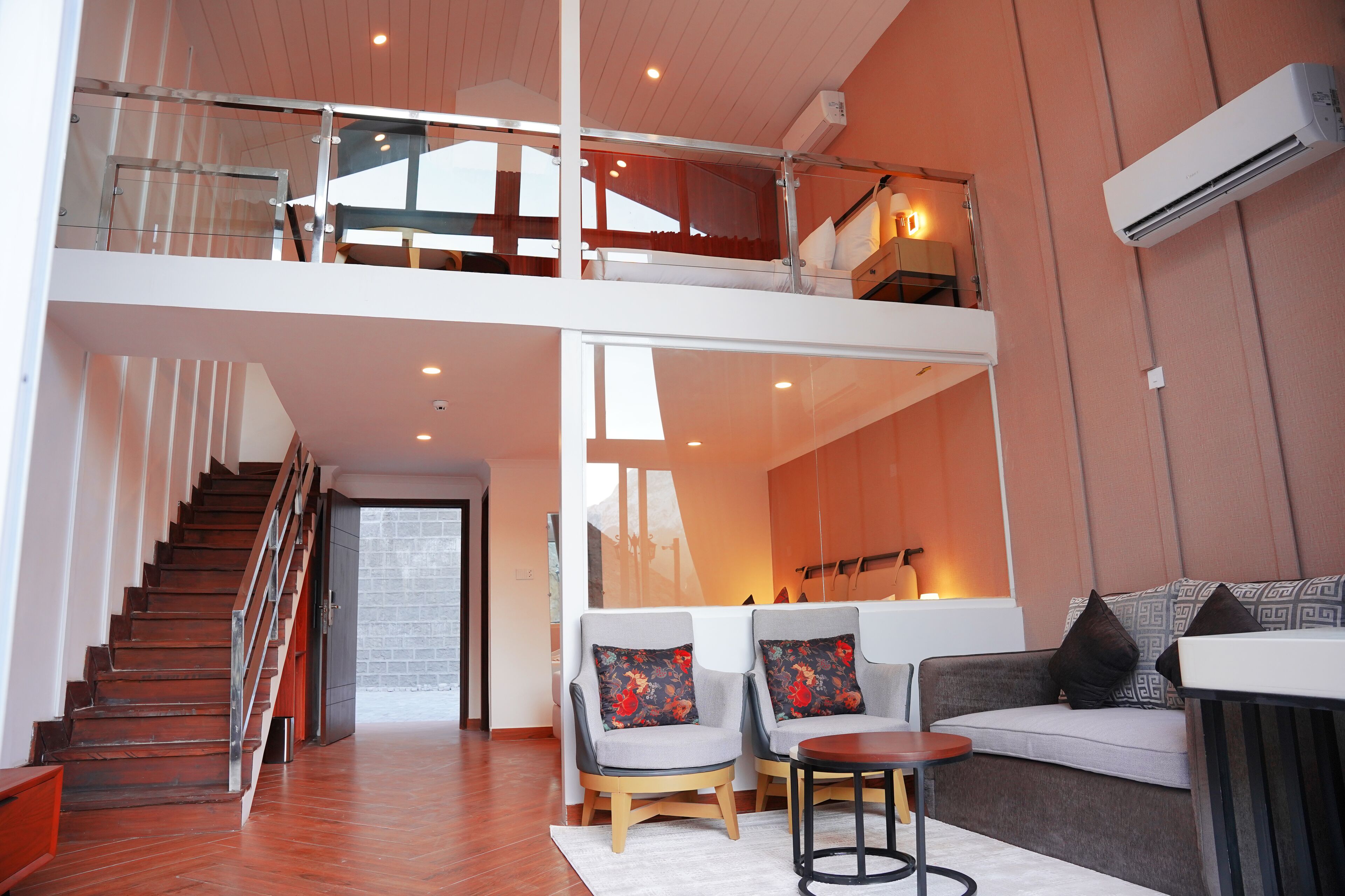 Amplia sala de estar con una escalera, un conjunto de sofás y una mesita.