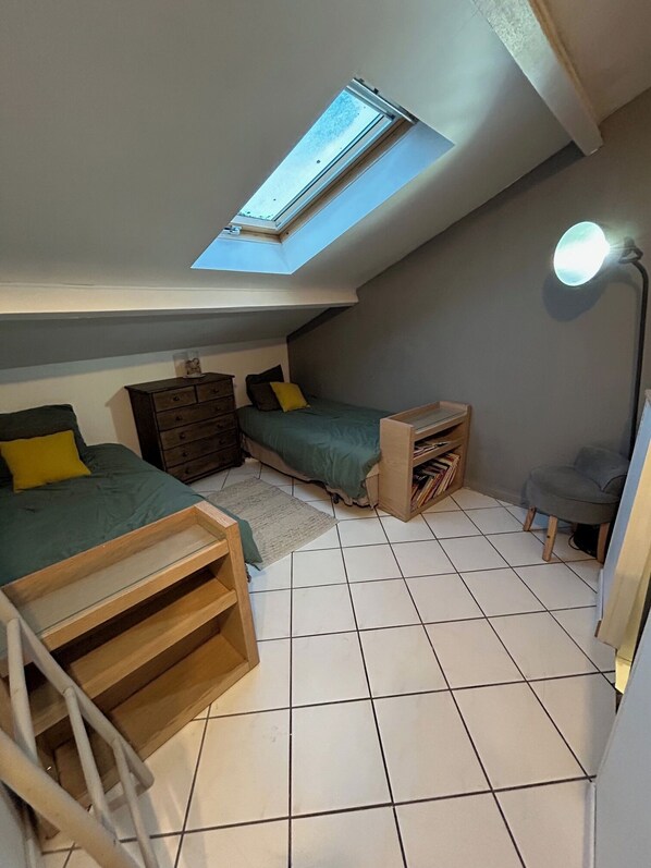 A compact room with a skylight, a bed, a desk, and a chair.