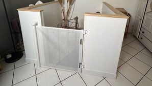 Una habitación con un separador blanco, un televisor fijado a la pared y piso de baldosas.