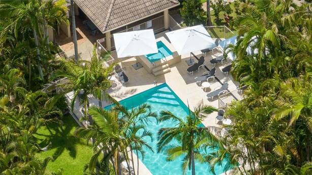 An aerial view of a resort with a swimming pool surrounded by palm trees and outdoor seating areas with umbrellas. - Miami Beachside Holiday Retreat (Miami)