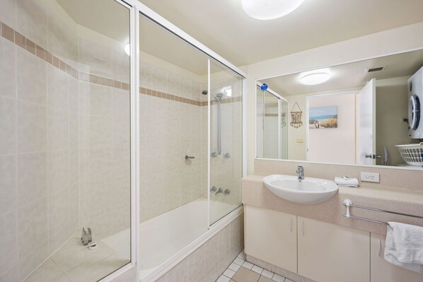 Un baño moderno con ducha de vidrio, lavamanos y espejo.