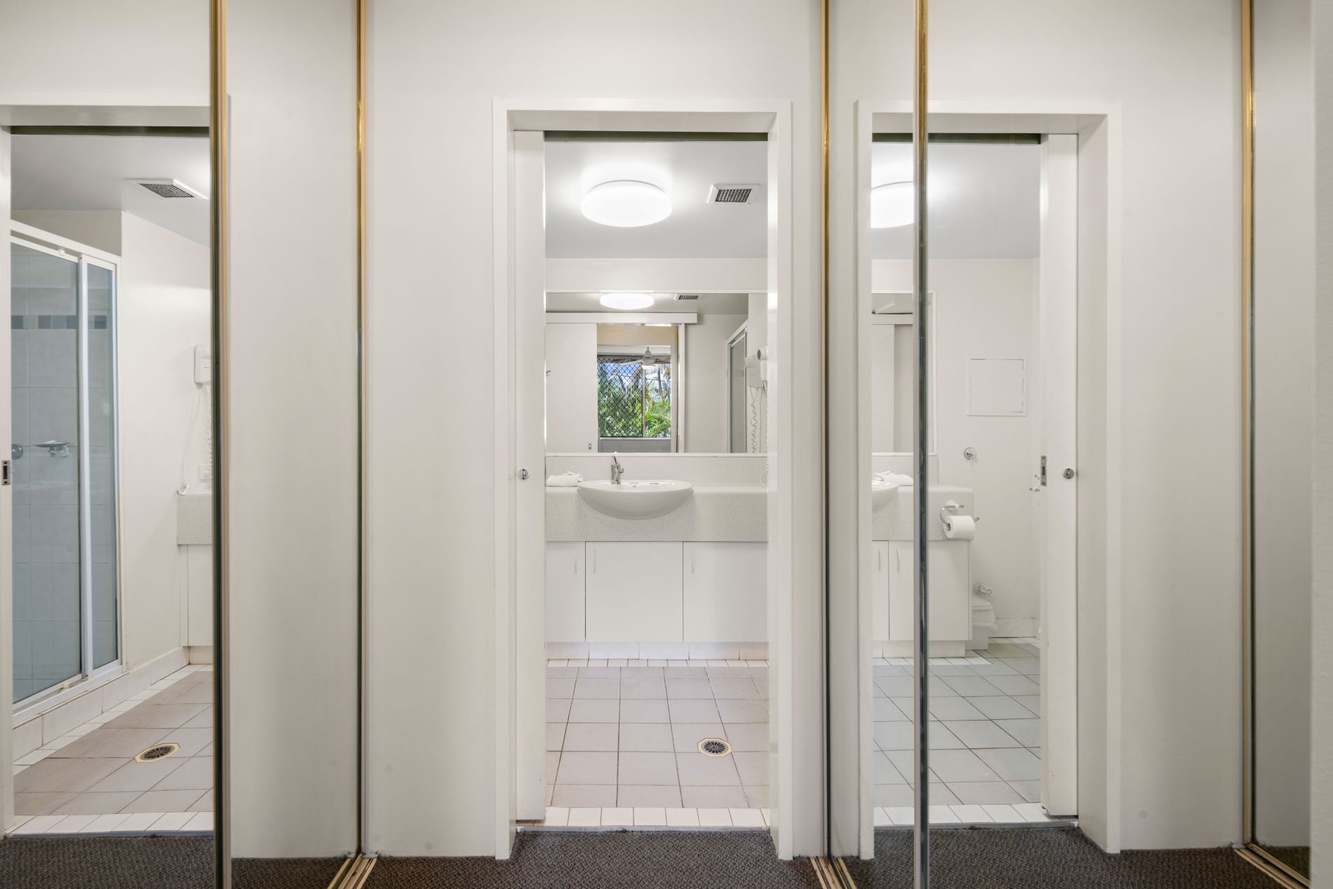 A hotel bathroom with a sink, mirror, and shower.