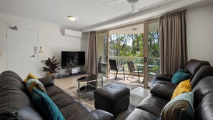 A modern living room with a sofa set, a TV, and a balcony with a view of palm trees. - Miami Beachside Holiday Retreat (Miami)