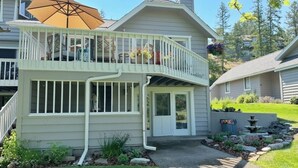 Ein zweistöckiges Haus mit Balkon, überdachter Terrasse und kleinem Garten mit Brunnen.