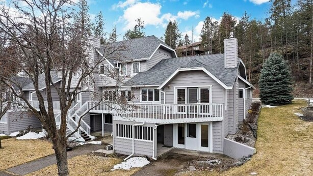 Ein zweistöckiges Haus mit Balkon, einer Treppe und einem Hof mit Bäumen und schneebedecktem Boden.