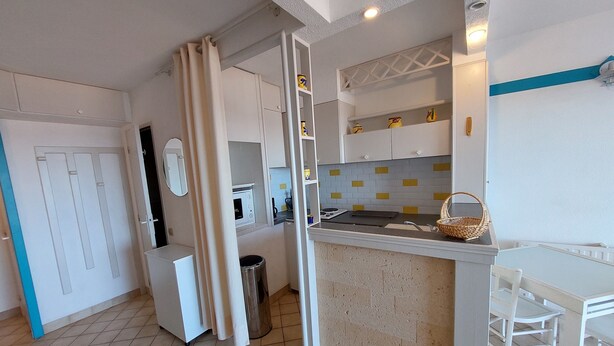 A compact kitchen with a microwave, sink, and white cabinets. A small dining area with a white table and chair is visible. - Location Banyuls-sur-Mer, Panoramic view (Banyuls sur mer)