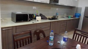 A kitchen with white cabinets, a microwave, a toaster, and a table with chairs. There are two bottles of water on the table. - 2 bedroom apartment with 2 pools (Cap Malheureux)