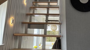 A modern interior with a staircase, wooden beams, and a clock on the wall. - Vacation in Finsterbergen in a cozy vacation home for 5 guests, idyllic location (Friedrichroda)