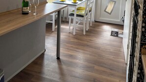 A modern kitchen with a wooden countertop, a dining area with yellow chairs, and a door with geometric patterns. - Vacation in Finsterbergen in a cozy vacation home for 5 guests, idyllic location (Friedrichroda)
