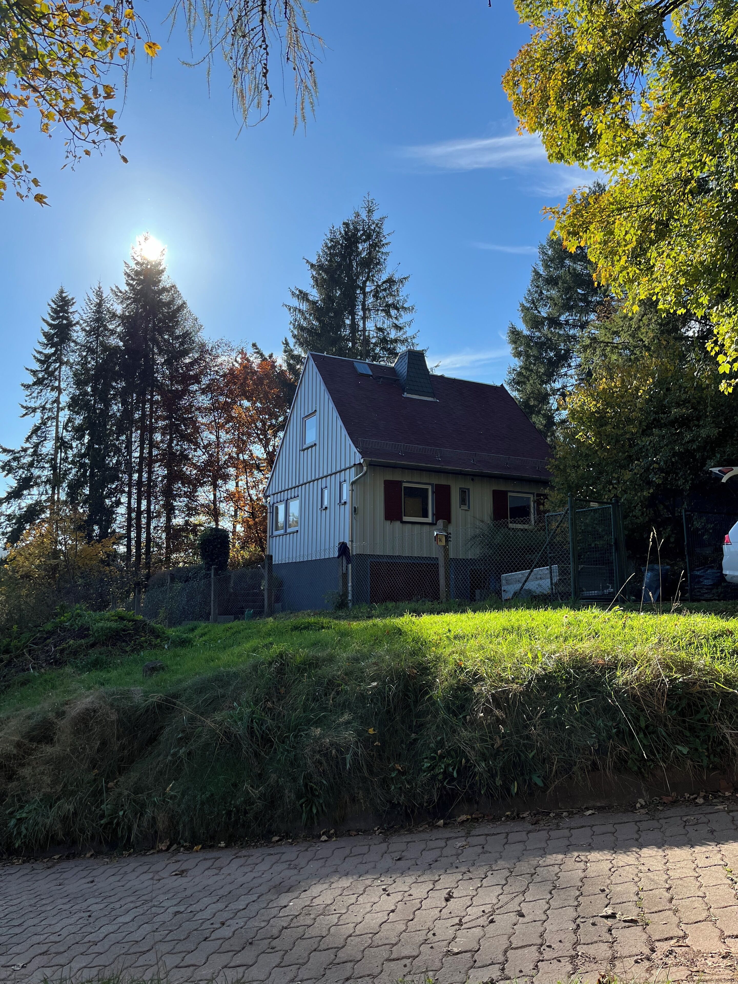 A two-story house with a sloped roof, surrounded by trees and a fence.