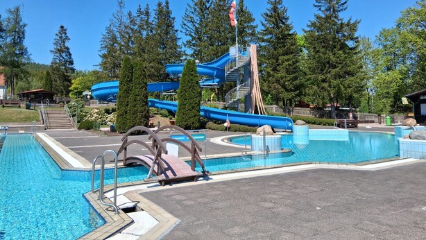 A swimming pool with a water slide and a flagpole. - Vacation in Finsterbergen in a cozy vacation home for 5 guests, idyllic location (Friedrichroda)