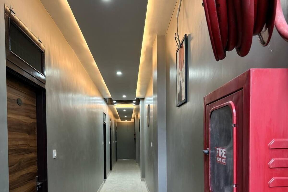 A hallway with a fire hose box on the right, a wooden door on the left, and a marble floor.