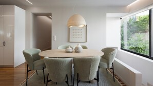 Un comedor moderno con una mesa redonda, seis sillas, una lámpara colgante y una ventana con vistas a zonas verdes.