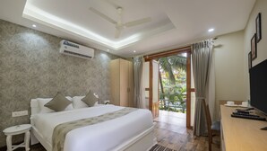 Un dormitorio con una cama grande, un escritorio con televisor, aire acondicionado y vistas al exterior.