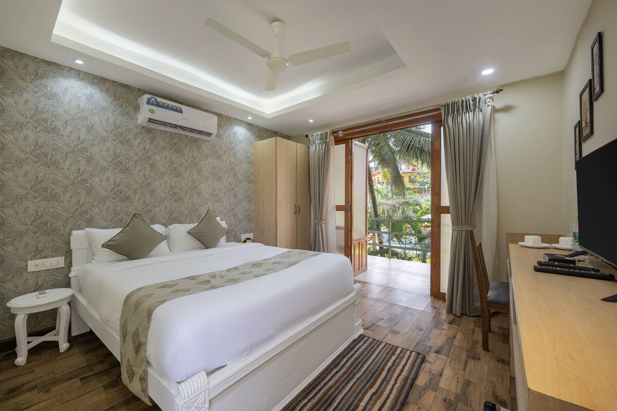 Een slaapkamer met een groot bed, een bureau met een televisie, een airconditioner en uitzicht op het omliggende landschap.