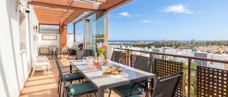 Een balkon met een eettafel, stoelen en uitzicht op de stad.
