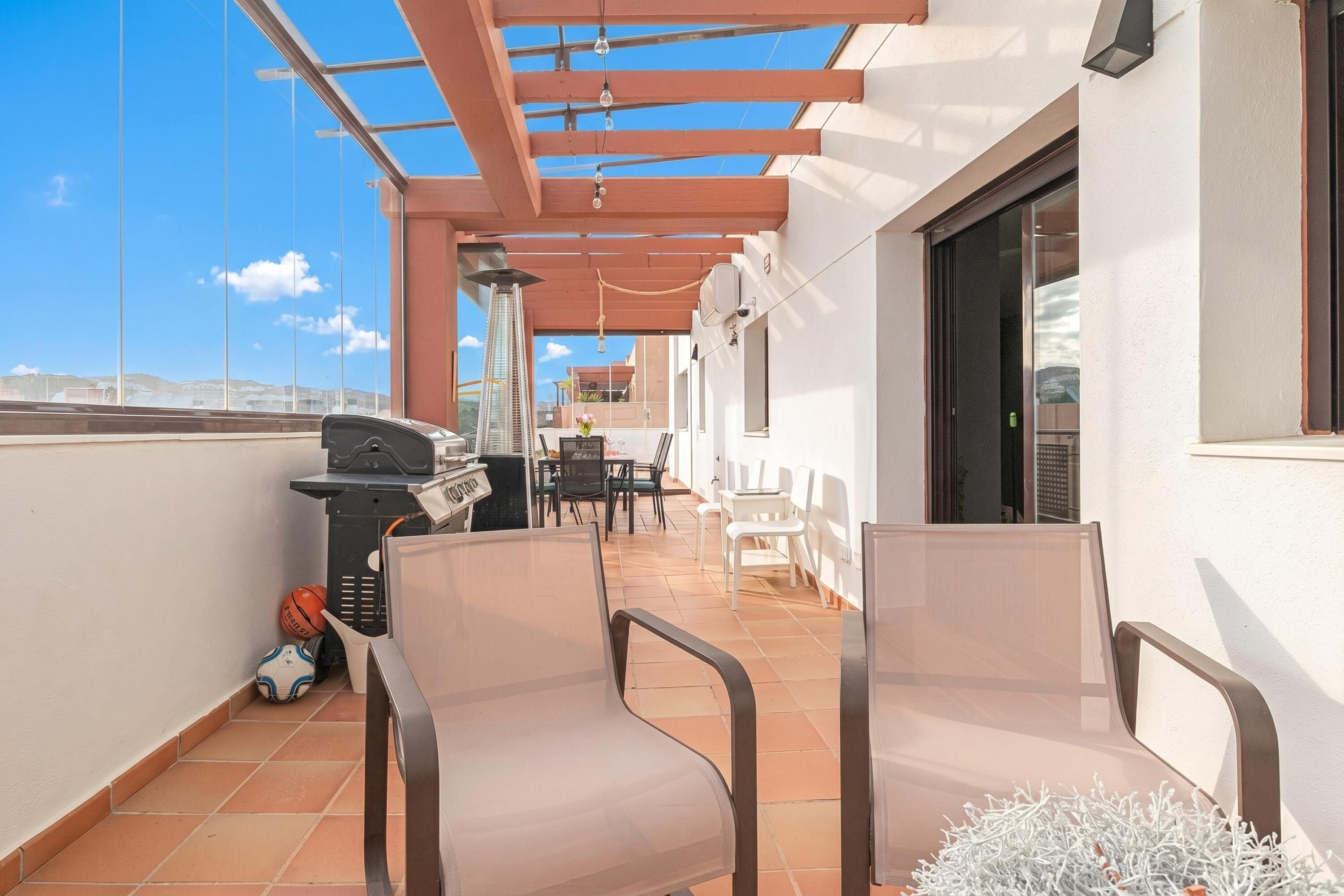 Un balcón con sillas, una parrilla y vistas de la ciudad.