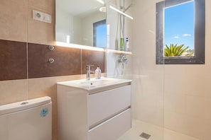 Un baño moderno con inodoro, lavabo y ducha.