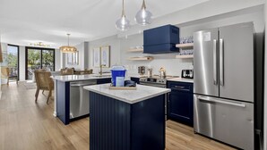 Una cocina moderna con una isla central, electrodomésticos de acero inoxidable e iluminación colgante.