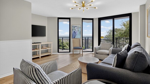 Una sala de estar moderna con un sofá, sillones, una mesa de centro y un televisor.