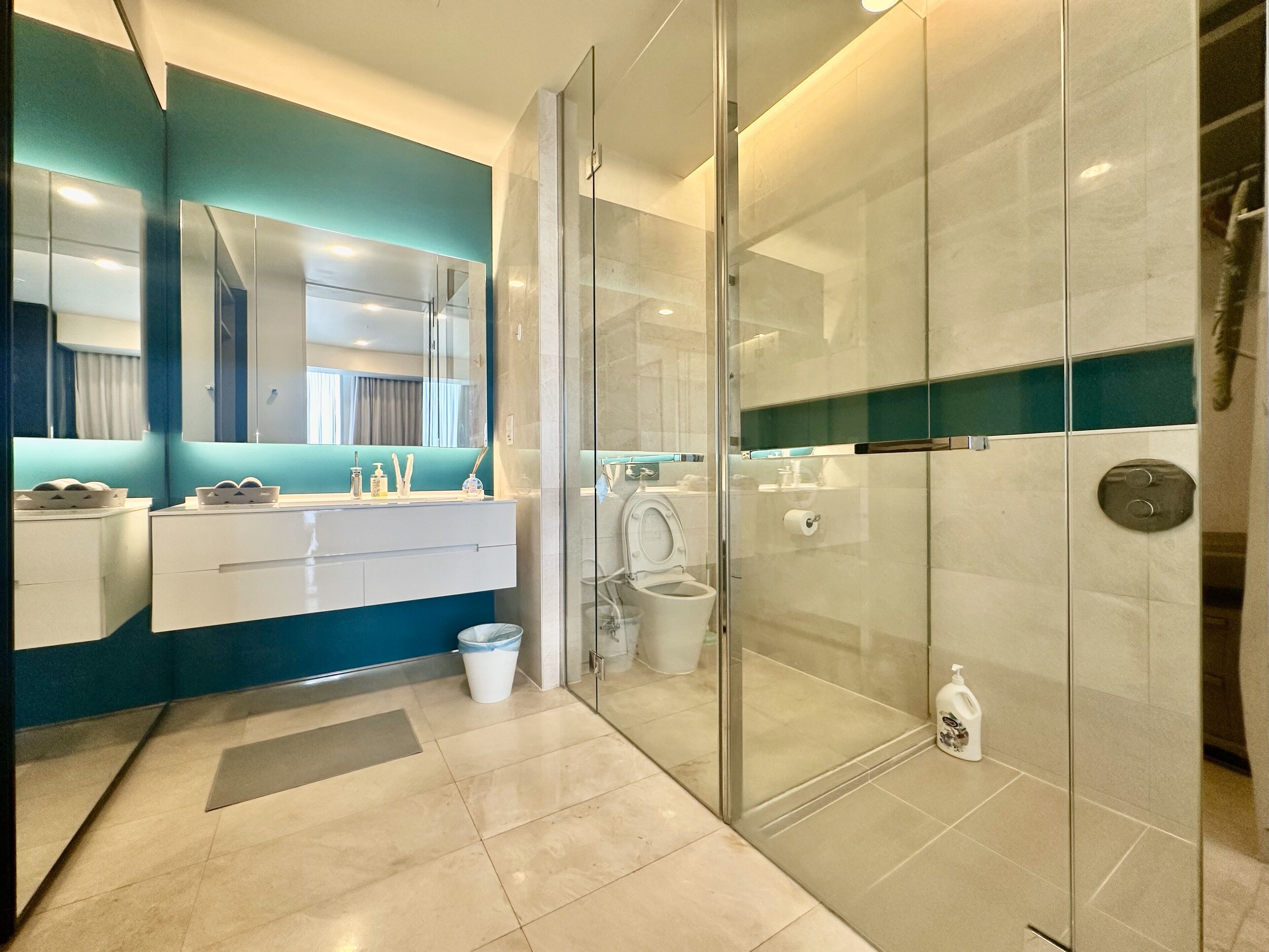 A modern bathroom with a glass-enclosed shower, a white vanity with a mirror, and a blue accent wall.