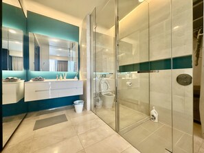 Un baño moderno con cabina de ducha de vidrio, tocador blanco con espejo y una pared de acento azul.