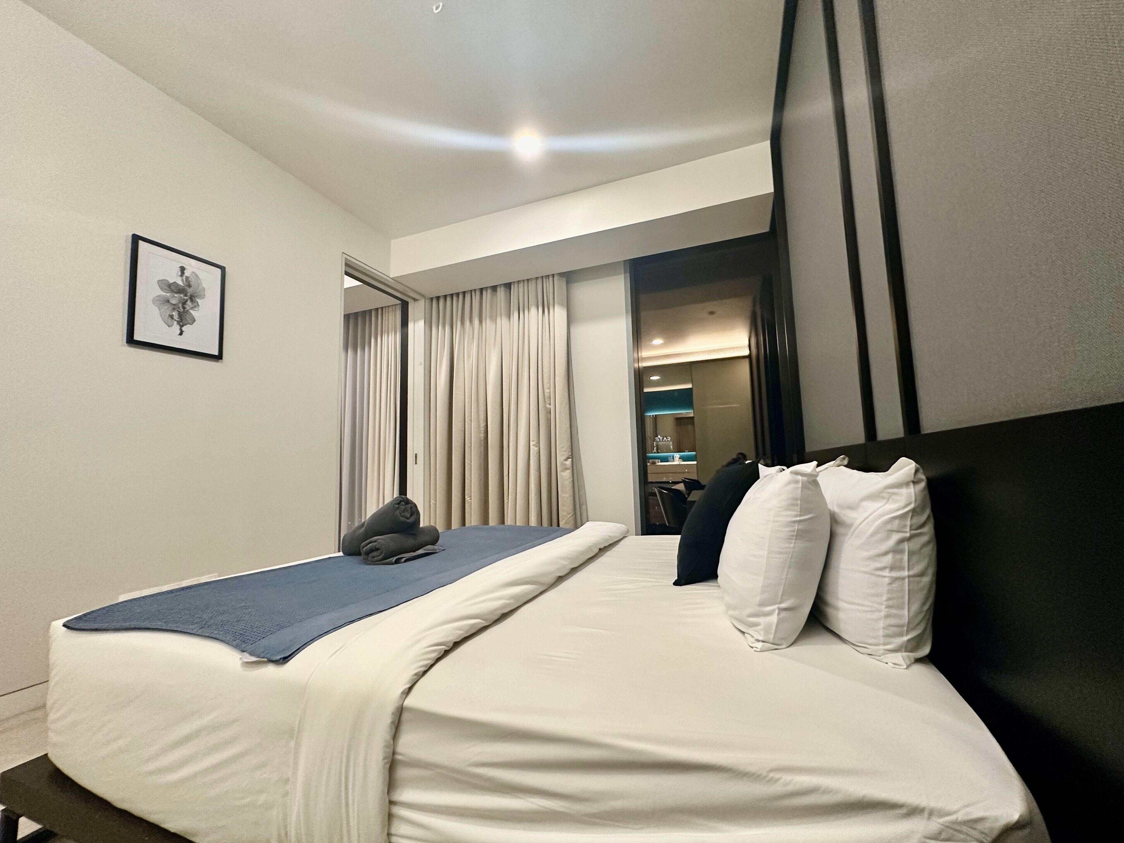 A hotel room with a bed, a framed picture on the wall, and a view into the bathroom.