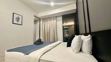 A hotel room with a bed, a framed picture on the wall, and a view into the bathroom.