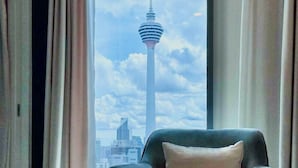 Una habitación con vistas a una torre alta y un paisaje urbano a través de una ventana con cortinas.
