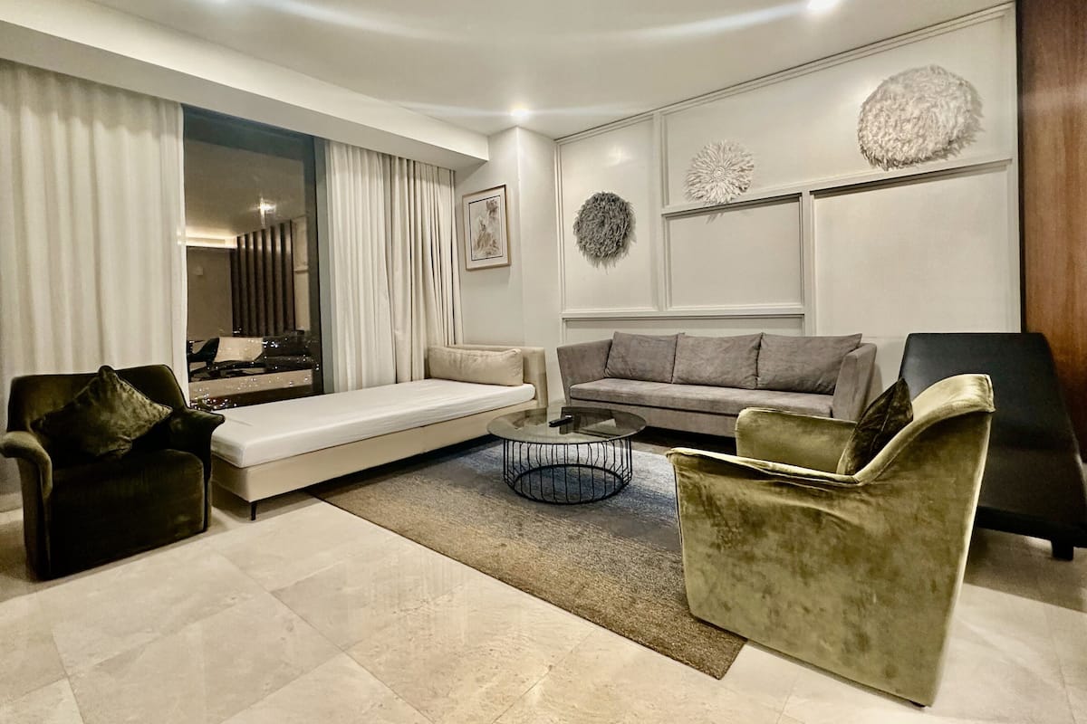 Una sala de estar moderna con un sofá, sillones, una mesa de centro y un espejo grande.