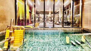 Una piscina interior con suelo de baldosas, rodeada por paredes de vidrio.