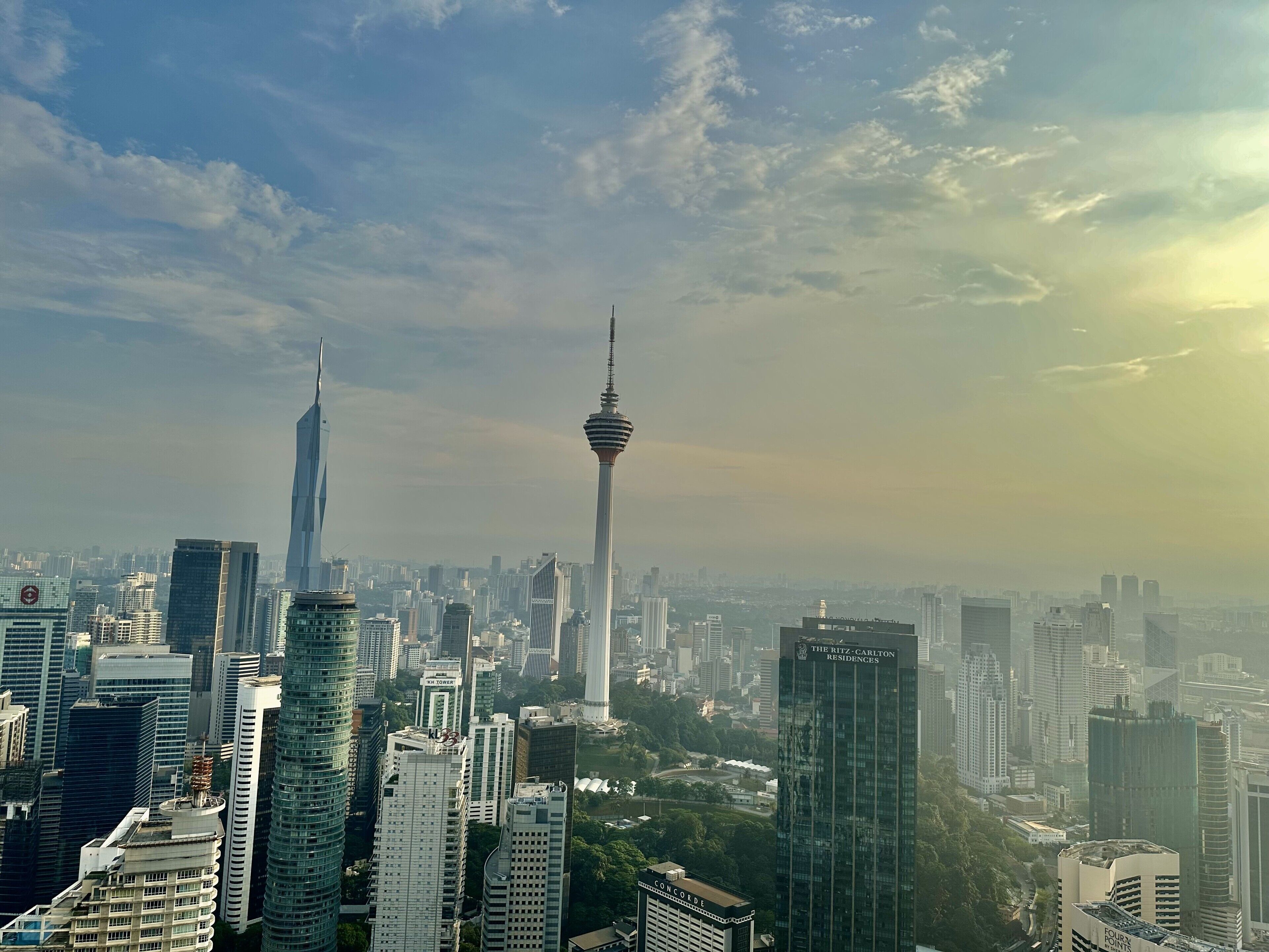 A cityscape with modern high-rise buildings, including a prominent tower and a skyscraper.